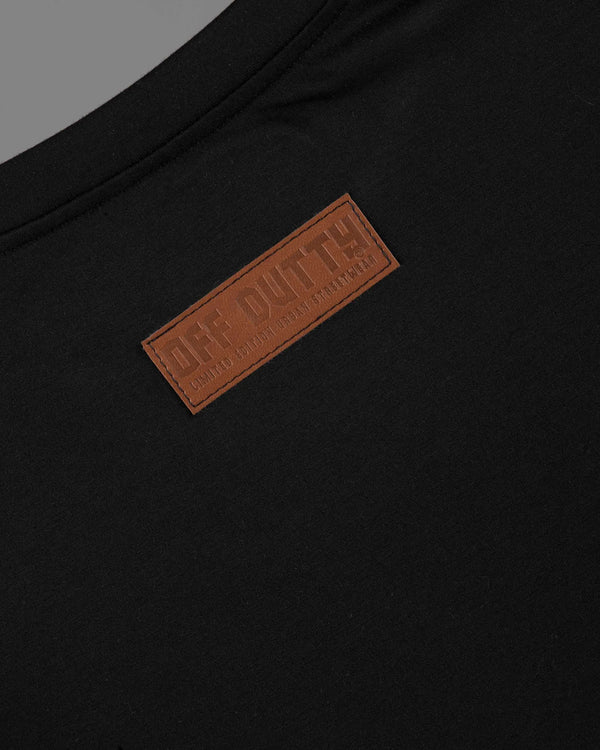 Close-up of the back of Off Dutty's 'What Is Happiness' black relaxed t-shirt, focusing on the leather tag stitched at the top center. The tag features the brand's logo and 'Limited Edition Urban Streetwear' engraved in the leather, highlighting the premium quality and exclusivity of the garment.