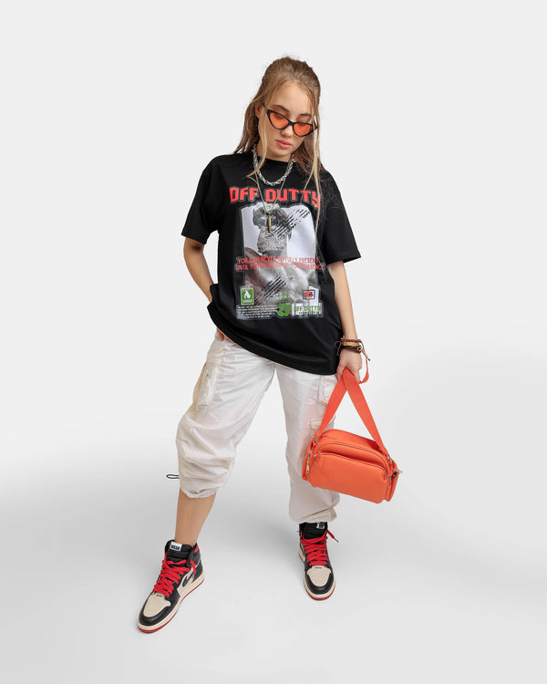 Fifth photo is A female Russian model in a dynamic pose, wearing Off Dutty's 'Embracing Your Presence' black relaxed t-shirt paired with white cargo pants and Air Jordan 1 Retro High OG NRG 'Not For Resale' sneakers. She complements her look with orange sunglasses and a matching handbag, exuding attitude as she gazes towards the t-shirt.