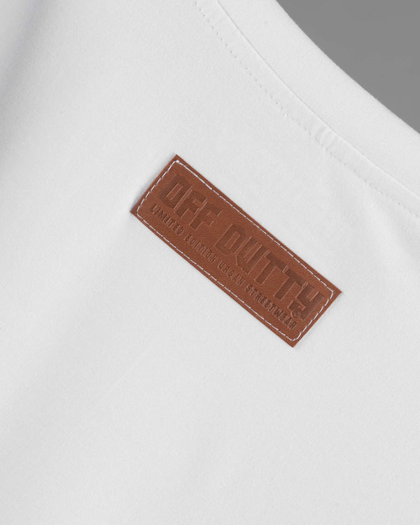 Close-up of the back of Off Dutty's 'What Is Happiness' white relaxed t-shirt, focusing on the leather tag stitched at the top center. The tag features the brand's logo and 'Limited Edition Urban Streetwear' engraved in the leather, highlighting the premium quality and exclusivity of the garment.